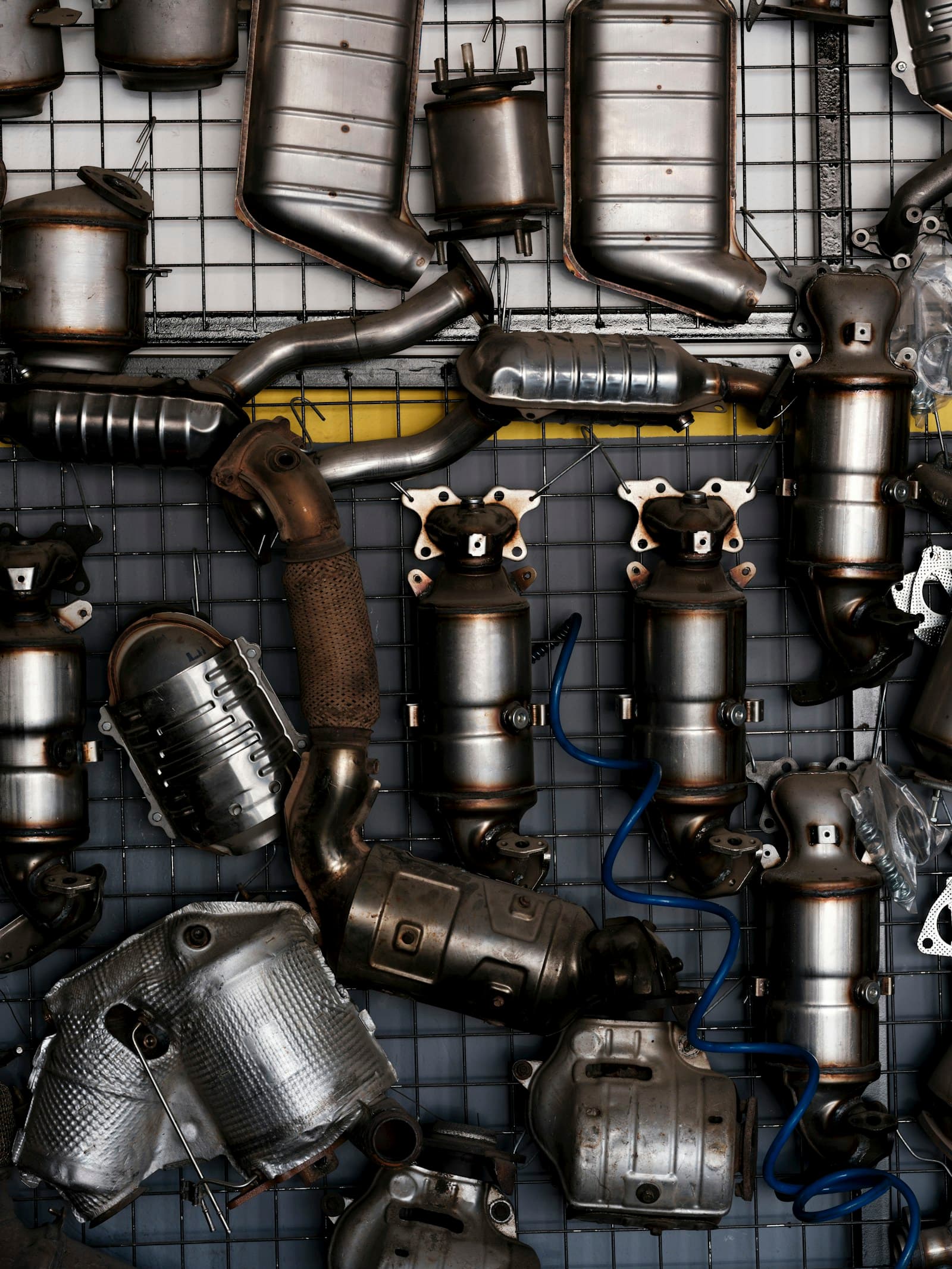 Assorted catalytic converters and exhaust components laid out for inspection